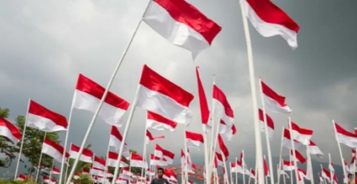 Warga melintasi deretan bendera merah putih yang dipasang di kebun teh Kemuning, Karanganyar, Jawa Tengah.